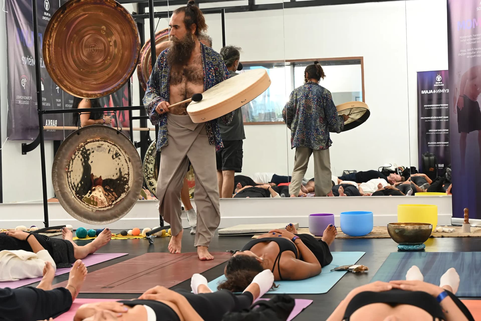 Matlar arasında davul çalarak ses meditasyonunu yöneten eğitmen
